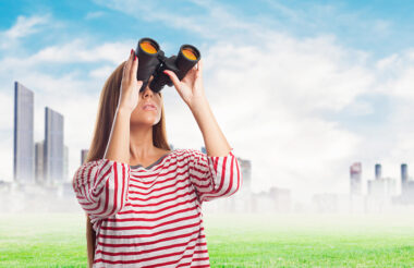 portrait of a young woman looking throught a binoculars